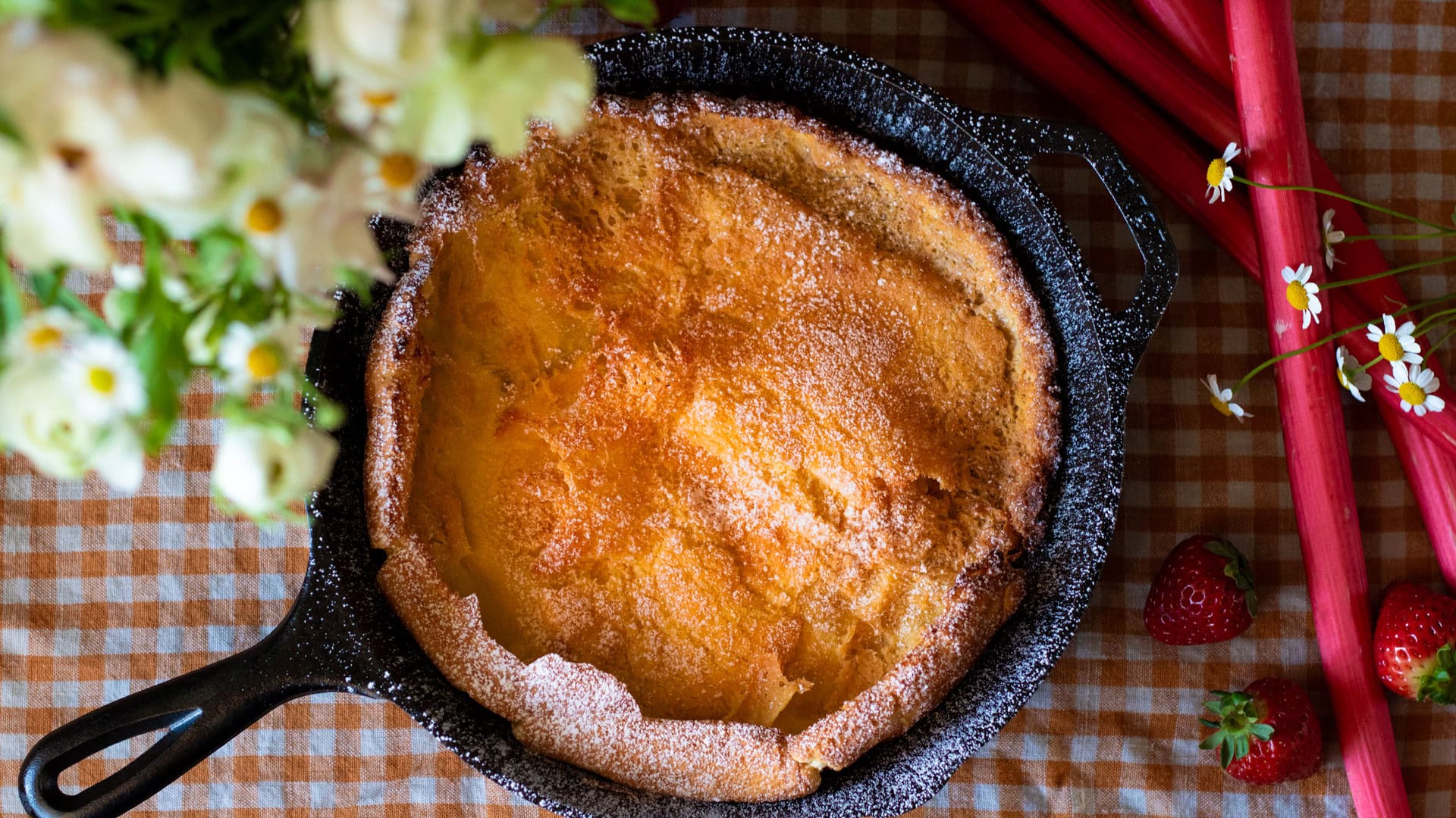 Plain dutch baby with flowers and fruit next to it